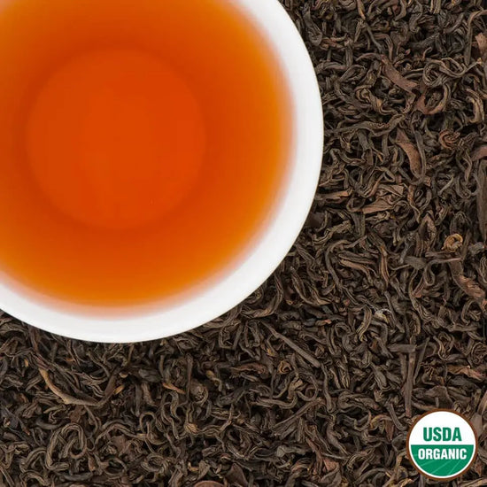 Annapurna Amber Organic Oolong Tea from Nepal – USDA Organic loose leaf with amber liquor in white cup on tea leaves