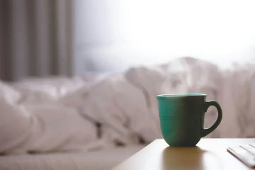 Organic bedtime tea in a steaming mug on a bedside table for better sleep