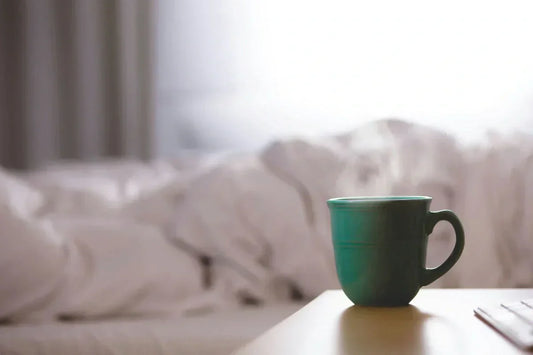 Organic bedtime tea in a steaming mug on a bedside table for better sleep
