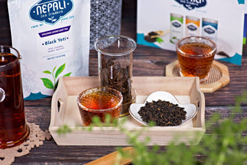 Loose leaf Black Yeti Oolong tea with brewed cups and packaging from Nepali Tea Traders on wooden tray