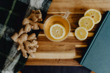 A soothing cup of ginger and lemon tea with honey on a wooden board, ideal for natural sore throat relief and cold recovery.