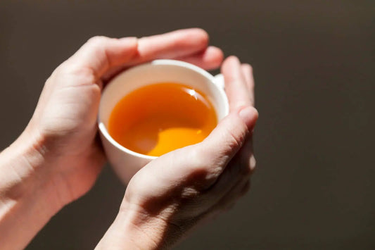Hands cradling a warm cup of Sherpa Breakfast Nepali black tea, the same strong brew used for a black tea hair rinse