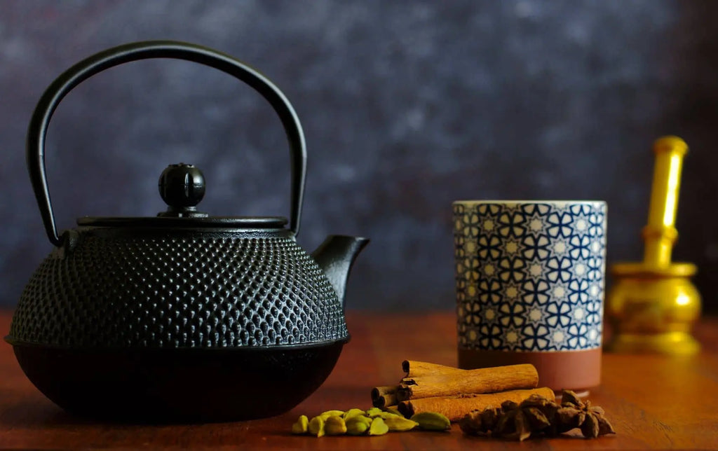 Traditional Nepali masala tea setup with spices, black kettle, and patterned cup on wooden table