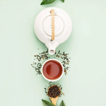 Top-down view of loose leaf tea with a white teapot and cup of brewed tea