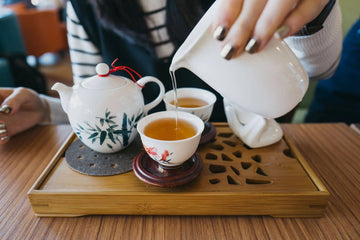 Pouring organic Nepali green tea into cups, pale-amber color