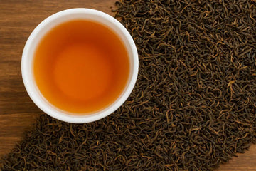 Cup of Nepali Sagarmatha Gold black tea with premium loose-leaf leaves on wood background