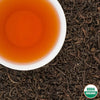 Annapurna Amber Organic Oolong Tea from Nepal – USDA Organic loose leaf with amber liquor in white cup on tea leaves