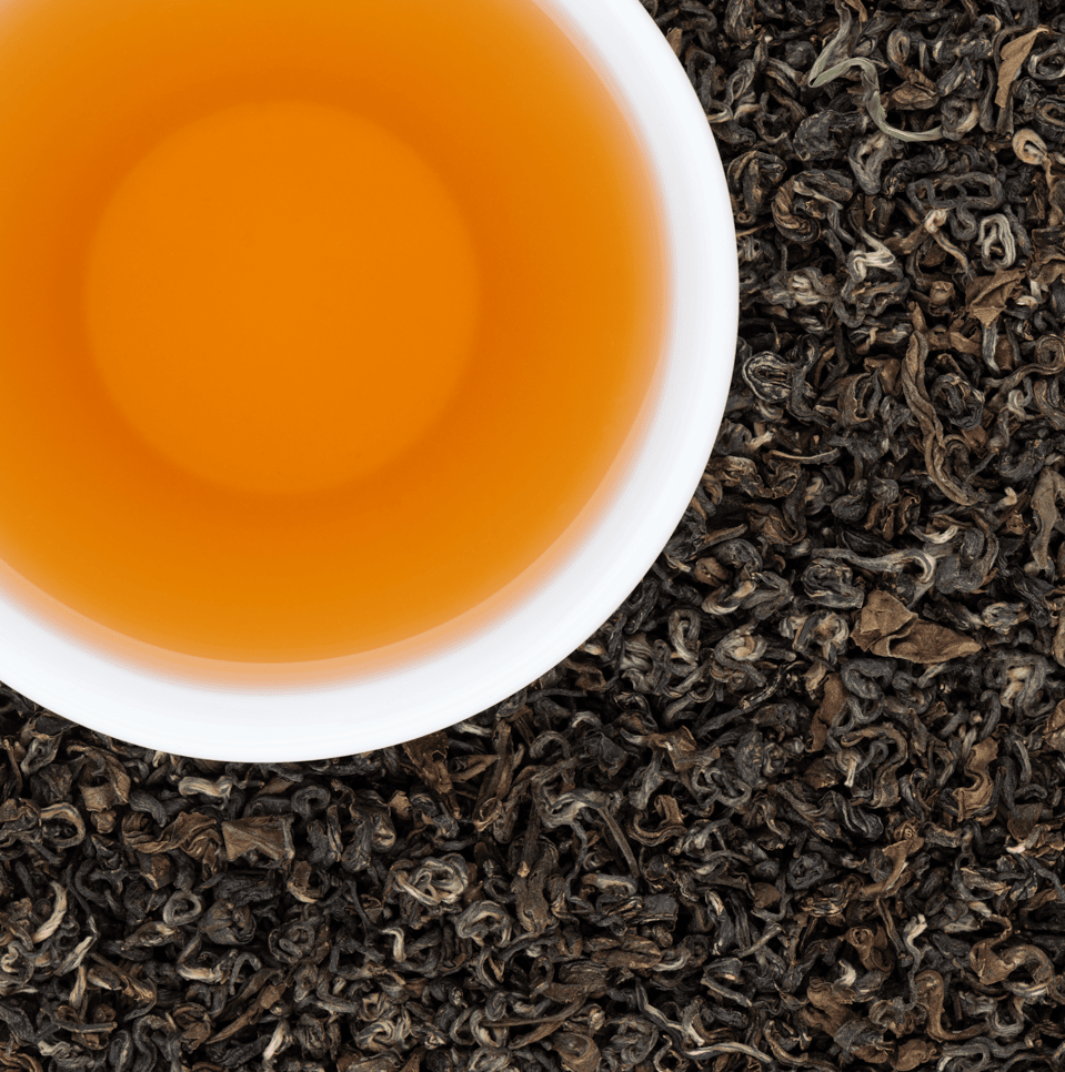 Orange-gold cup of Namche Oolong Tea on loose Nepali oolong leaves