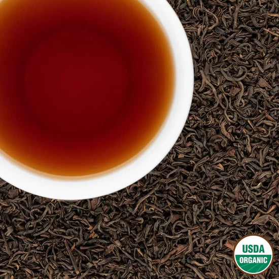 Ruby Organic Oolong Tea – USDA Organic loose leaf from Nepal with deep red brewed liquor in a white cup on tea leaves