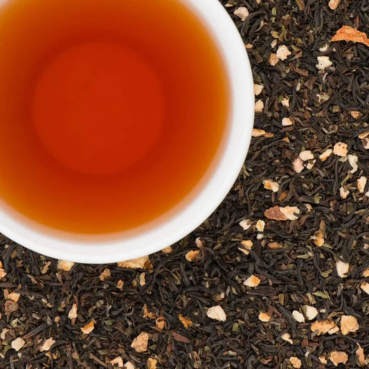 Overhead view of a rich amber cup of Everest Earl Gray tea with loose leaves and dried citrus peel.