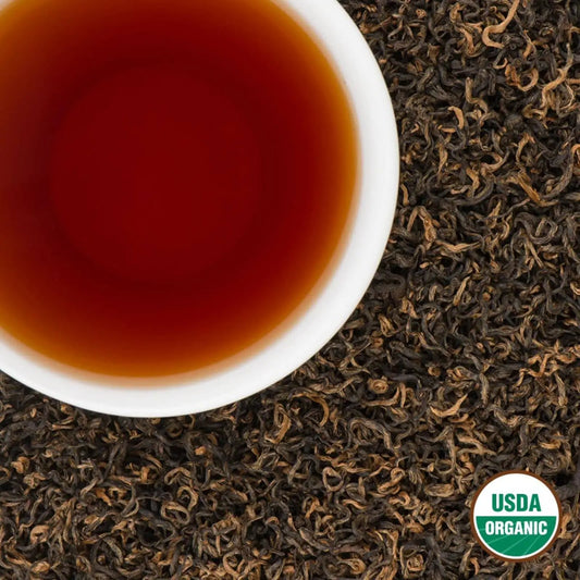 White cup of brewed Himalayan Golden Organic Black Tea on loose leaves with USDA Organic seal
