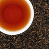 Deep amber cup of brewed Khumbu Organic black tea from Nepal with dark twisted loose leaves.