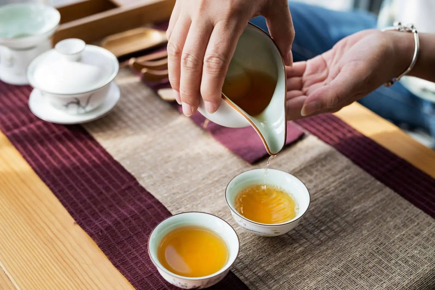 Amber Nepali oolong tea being poured into small cups in a traditional tea ceremony setting