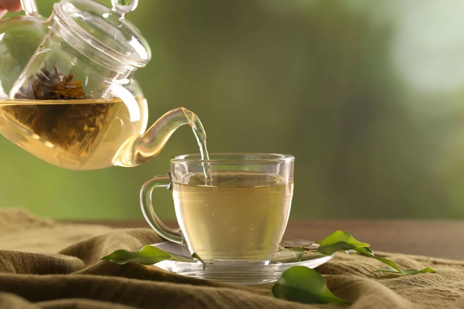 Organic Nepali loose leaf green tea poured from a glass teapot into a cup
