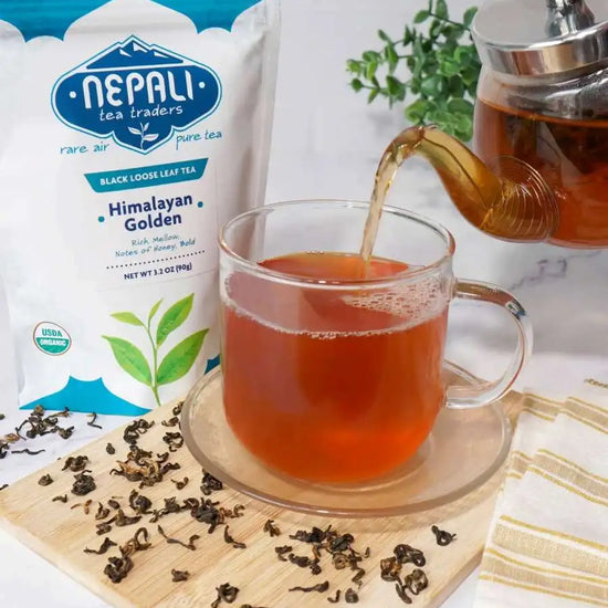 Freshly brewed cup of Himalayan Golden black tea being poured next to its high-barrier freshness pouch.