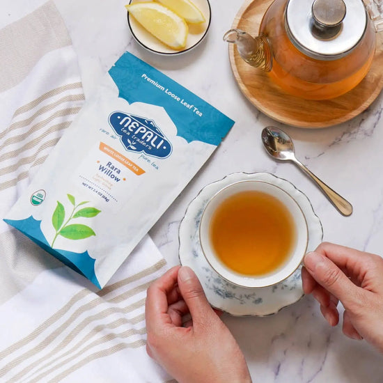 Rara Willow Organic White Tea from Nepal—Nepali Tea Traders pouch with a brewed teacup, glass teapot, and lemon slices.