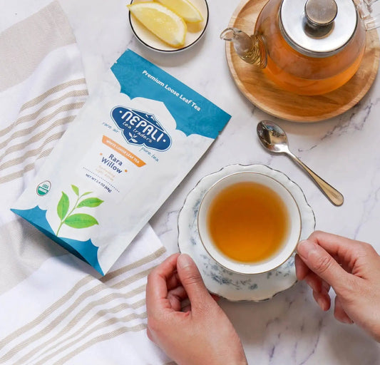 Rara Willow Organic White Tea from Nepal—Nepali Tea Traders pouch with a brewed teacup, glass teapot, and lemon slices.