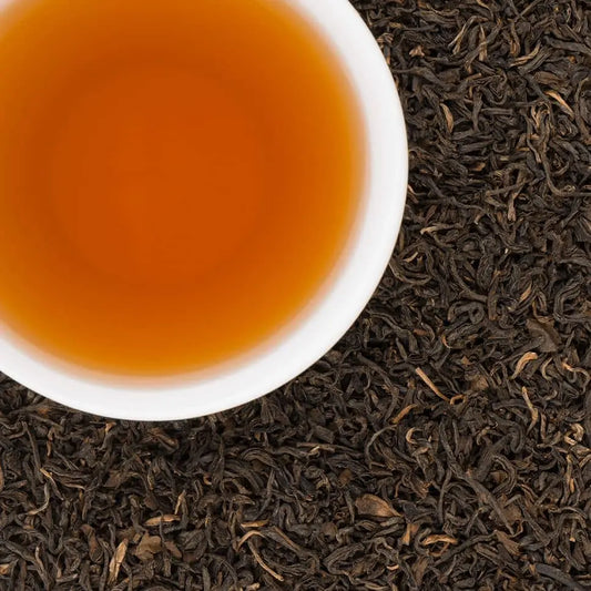 Cup of brewed Sherpa Breakfast Nepali black tea with loose leaf black tea background