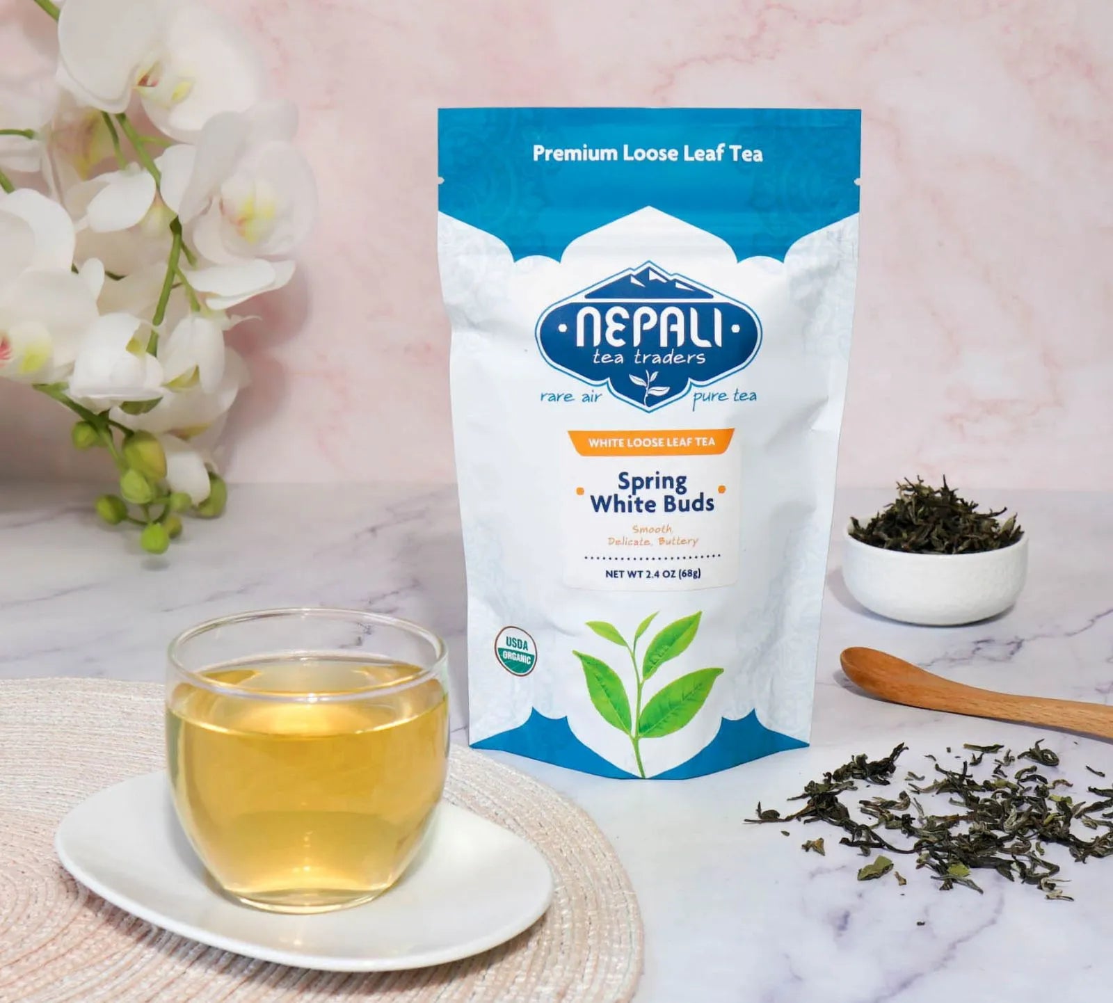 Spring White Buds organic white tea from Nepal—Nepali Tea Traders pouch with a brewed cup and loose leaves.