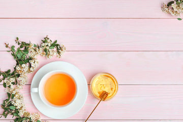 A cup of green tea served with honey and fresh jasmine flowers, illustrating natural sweeteners for tea.